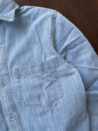Ice blue denim shirt pocket detail with contrast stitching and button placket