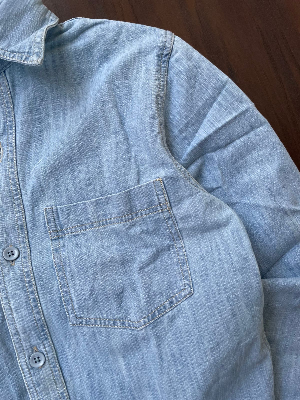 Ice blue denim shirt pocket detail with contrast stitching and button placket