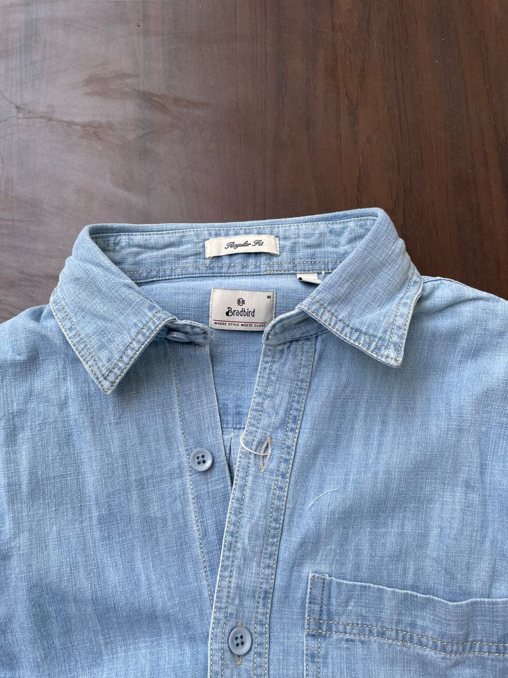 Ice blue denim shirt close-up showing pointed collar, buttons, and chest pocket