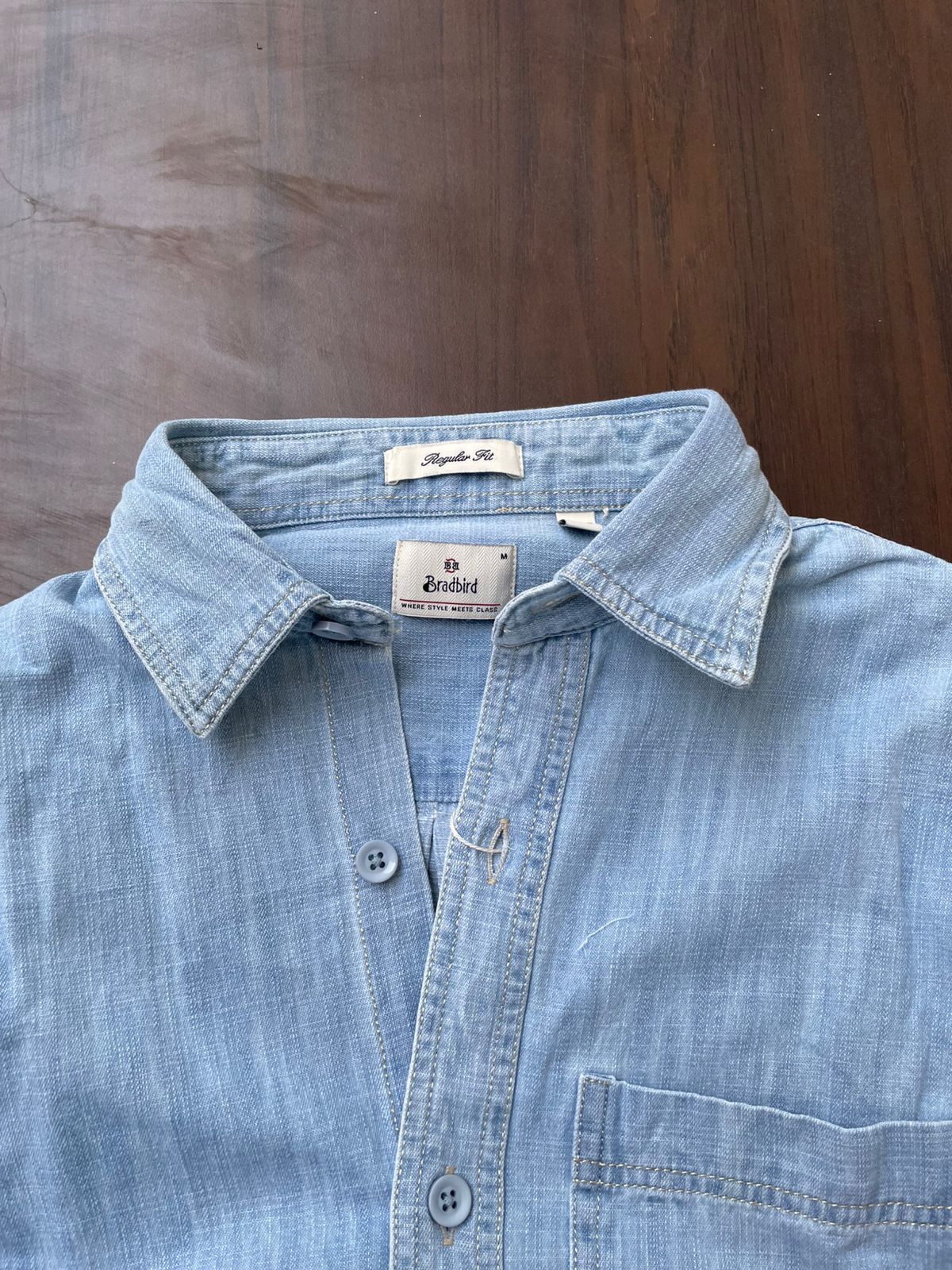 Ice blue denim shirt close-up showing pointed collar, buttons, and chest pocket