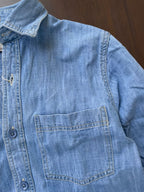 Light-wash denim shirt close-up of chest pocket and button placket with tonal buttons