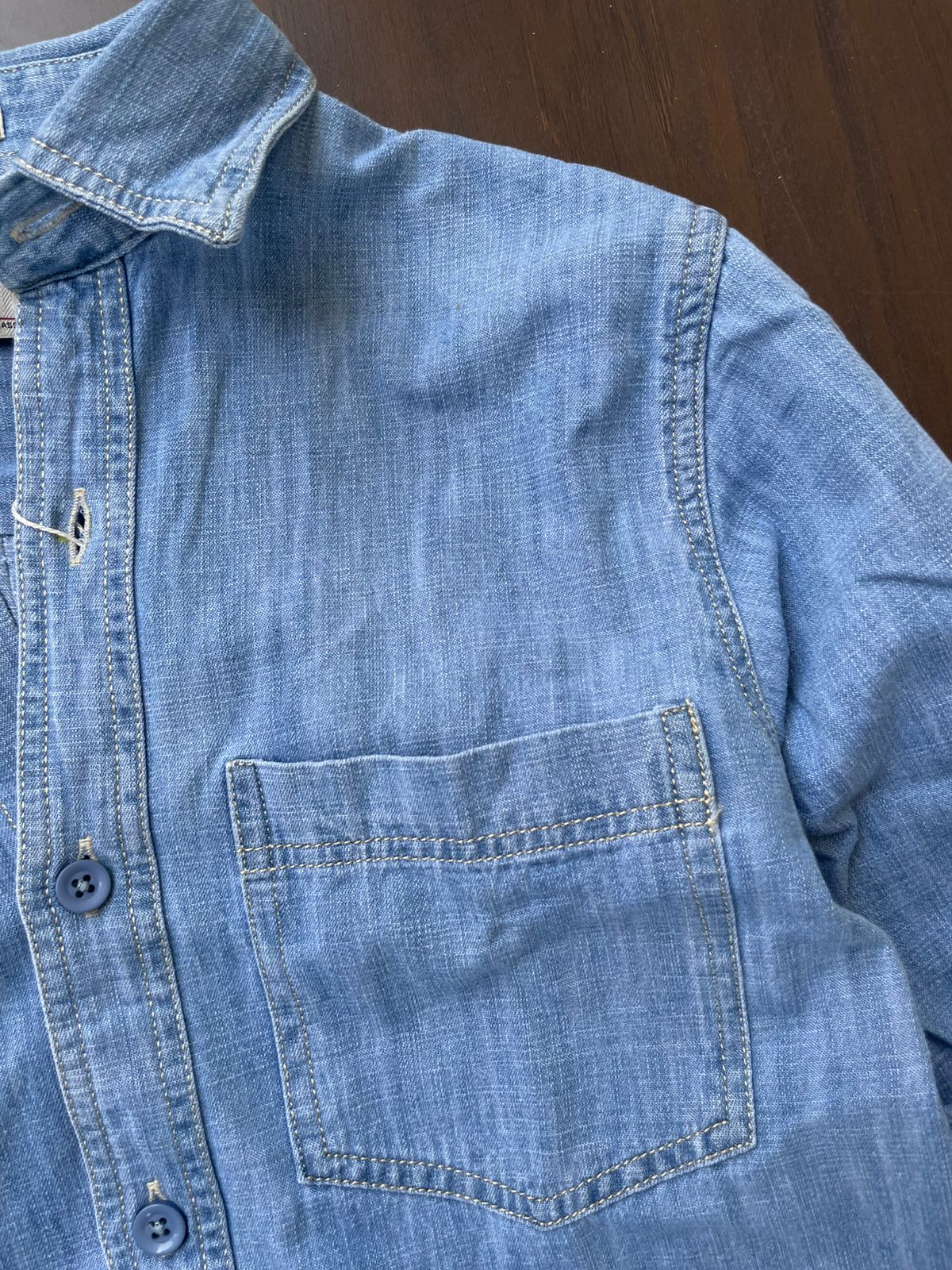 Light-wash denim shirt close-up of chest pocket and button placket with tonal buttons