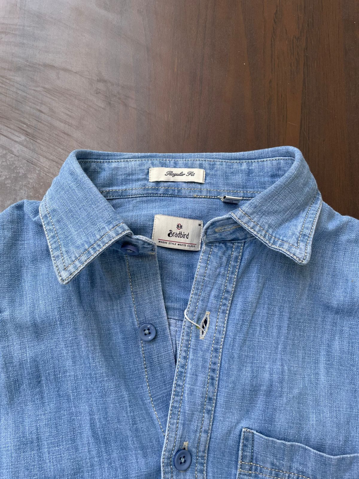 Light-wash denim shirt collar and button placket with interior brand tag and tonal buttons