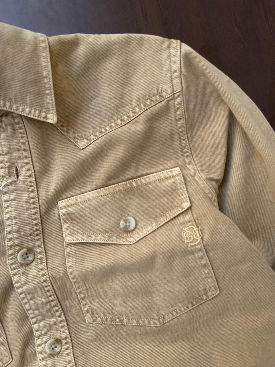 Tan beige denim western shirt chest pocket with flap and button; logo patch on pocket