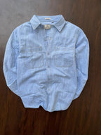Men's light-wash denim shirt laid flat with point collar and two chest pockets