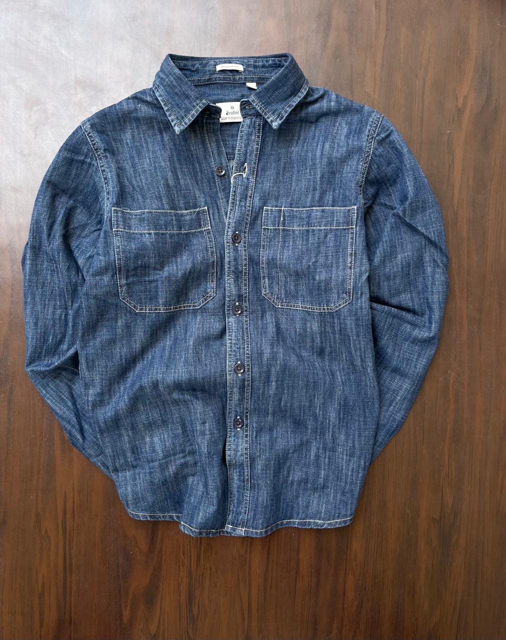 Stonewash indigo denim shirt featuring button front, collared neck, and two chest pockets