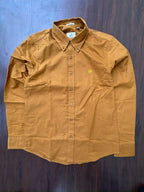 Mustard oxford button-up shirt laid flat, contrast monogram on left chest