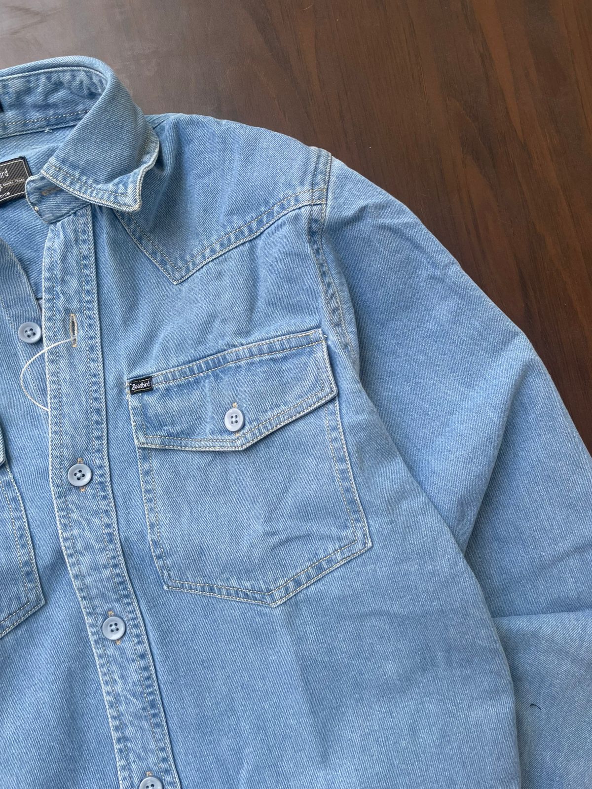 Light blue denim shirt pocket detail with buttoned placket