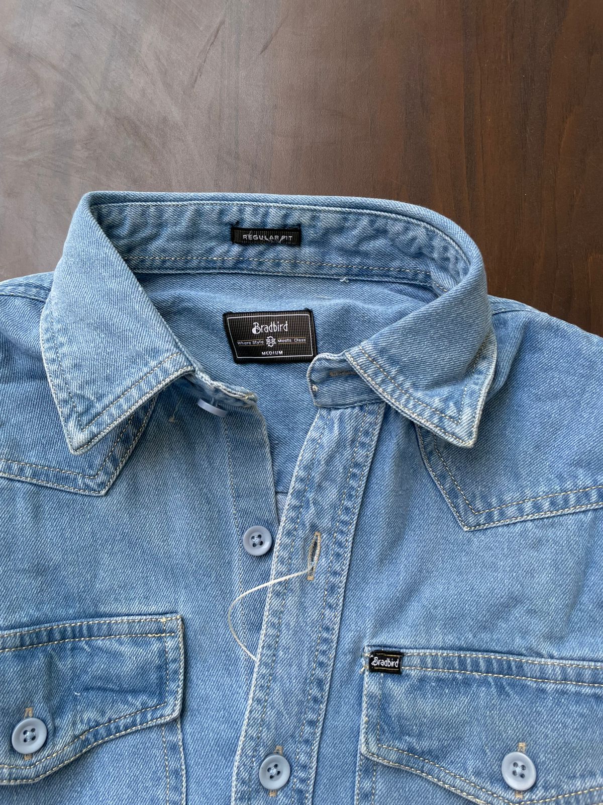 Light blue denim shirt collar and button placket, with brand label