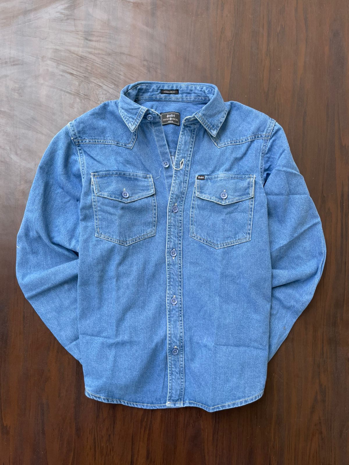 Medium wash denim western shirt laid flat with two chest flap pockets