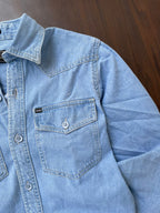 Light wash denim over-shirt close-up: flap chest pocket and snap buttons