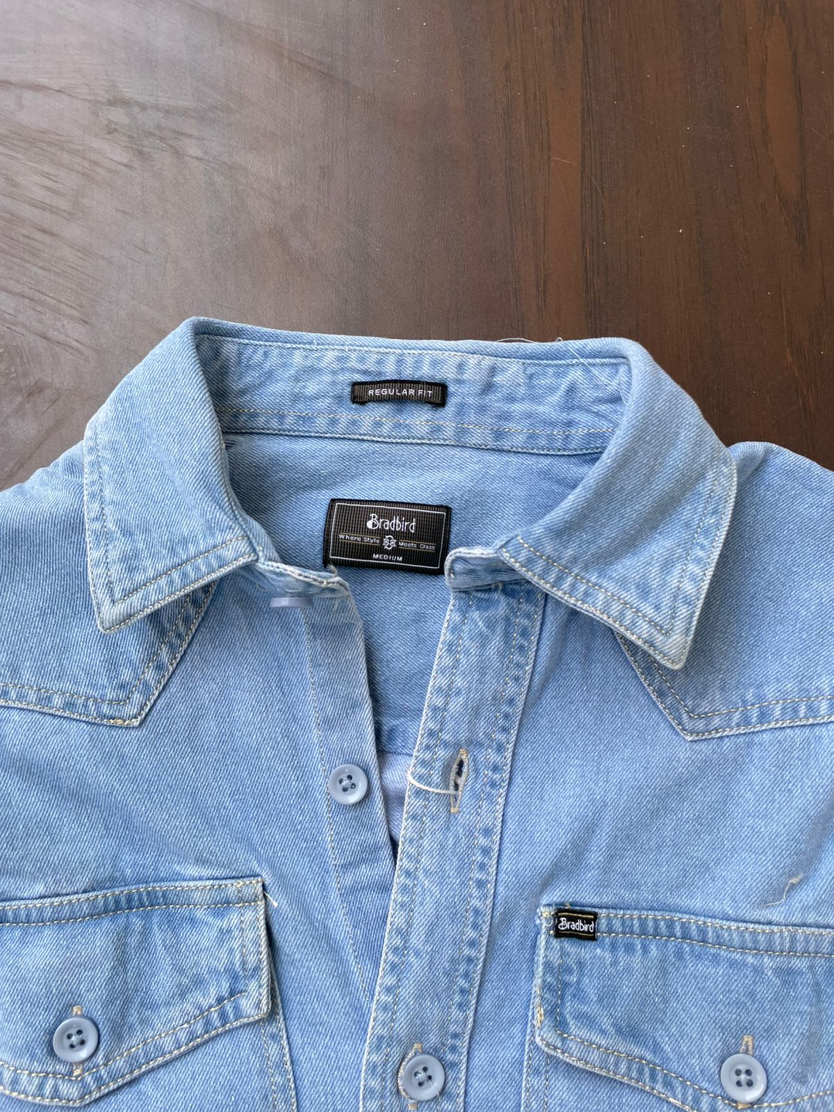 Light wash denim over-shirt close-up of neck label and snap-front placket