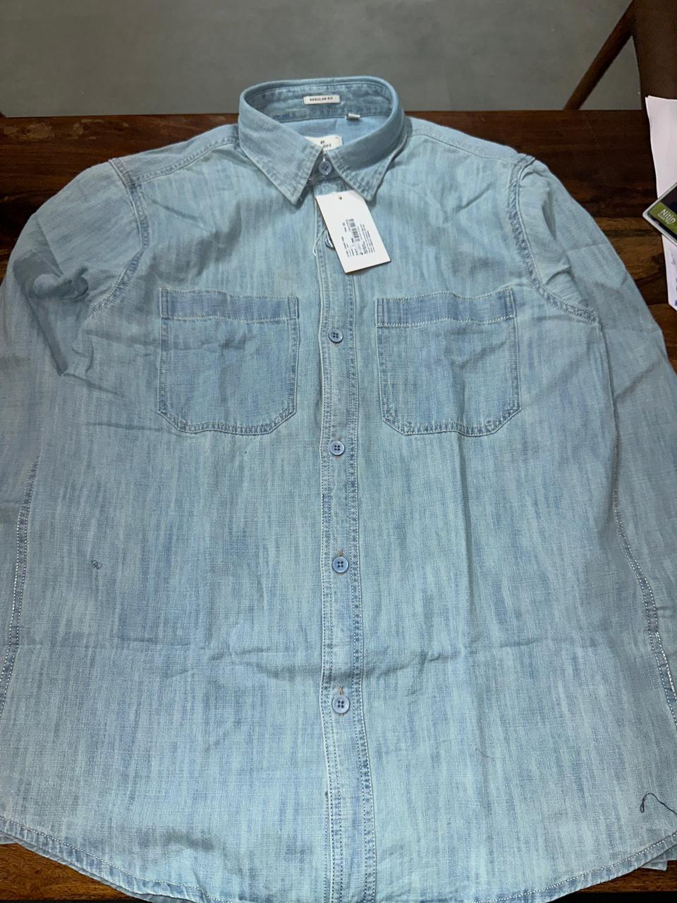 Light blue denim button-up shirt with two front chest pockets and collar