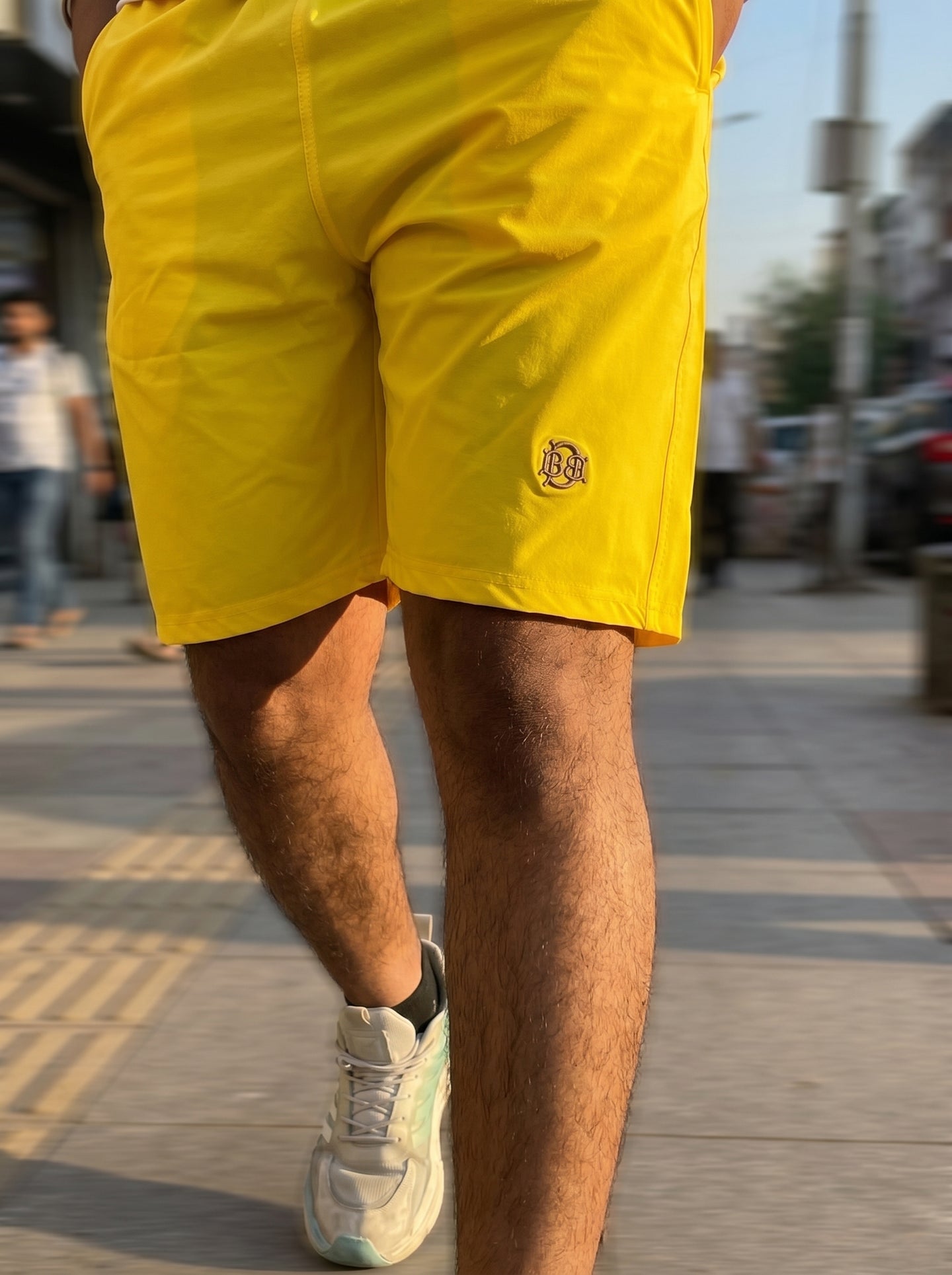 Bright yellow casual shorts, side logo on leg with stitched seams and mid-thigh length