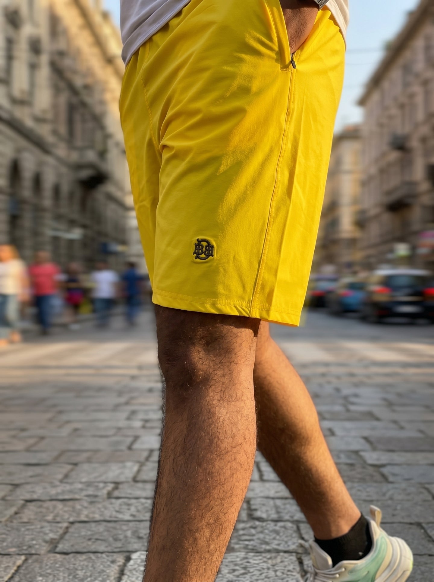 Bright yellow casual shorts, side logo patch and zipper fly seam, mid-thigh cut
