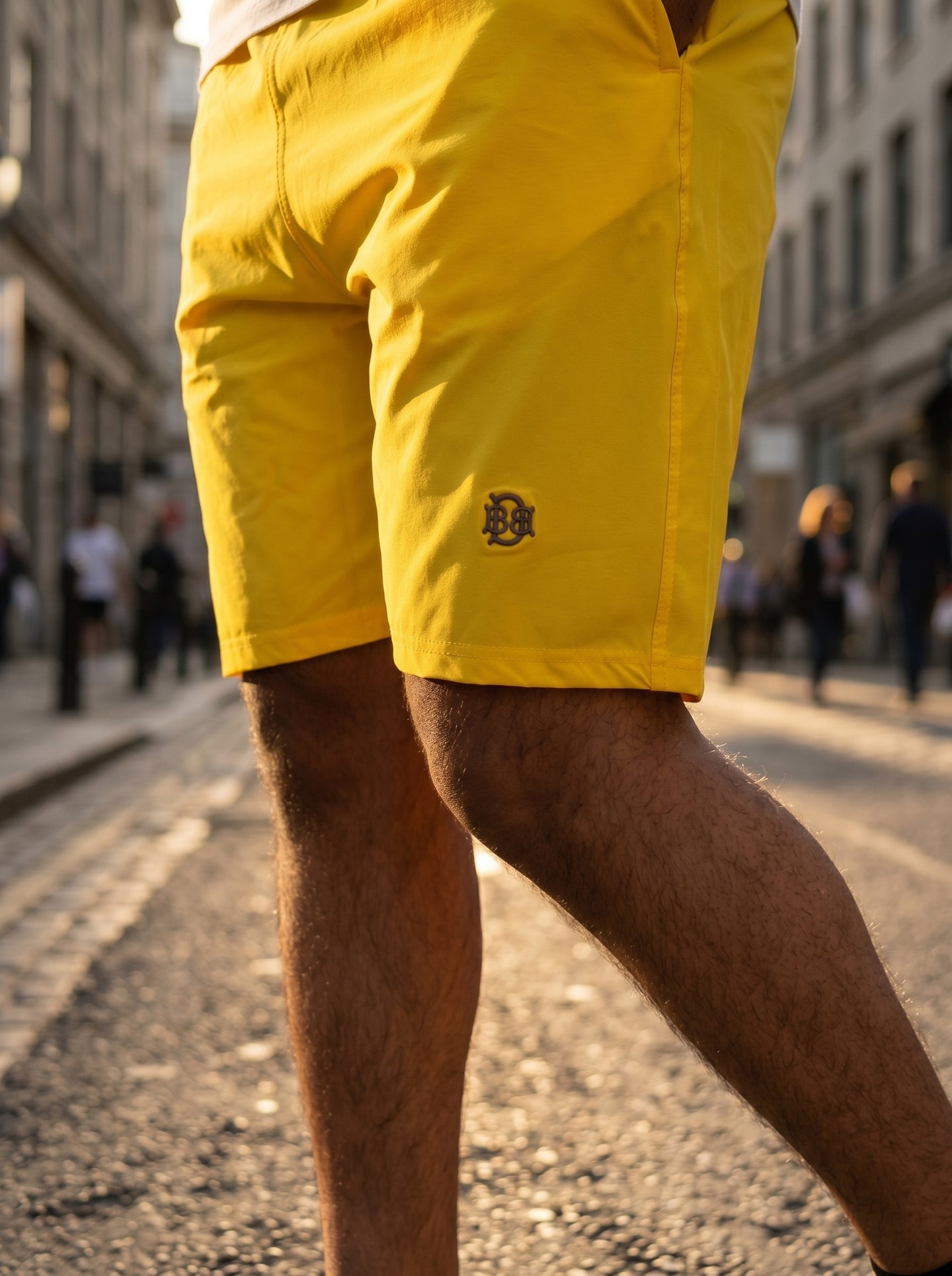 Bright yellow shorts front side view, BQ logo on hem and side pocket opening